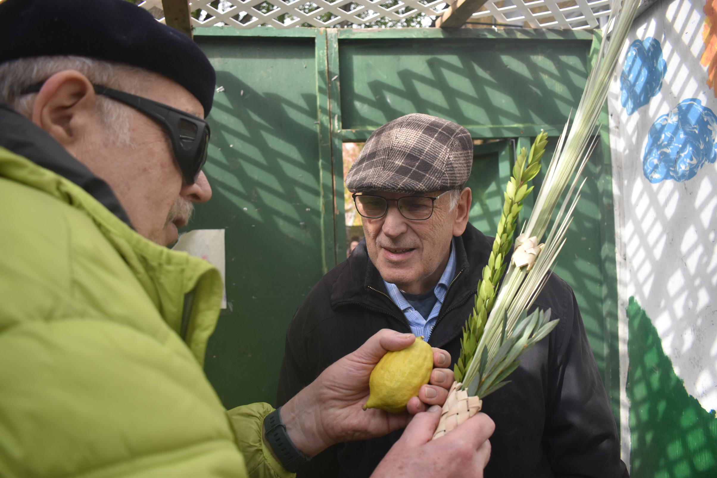 Image of two elder man having discussion, with man in foreground holding a lemon and plants.