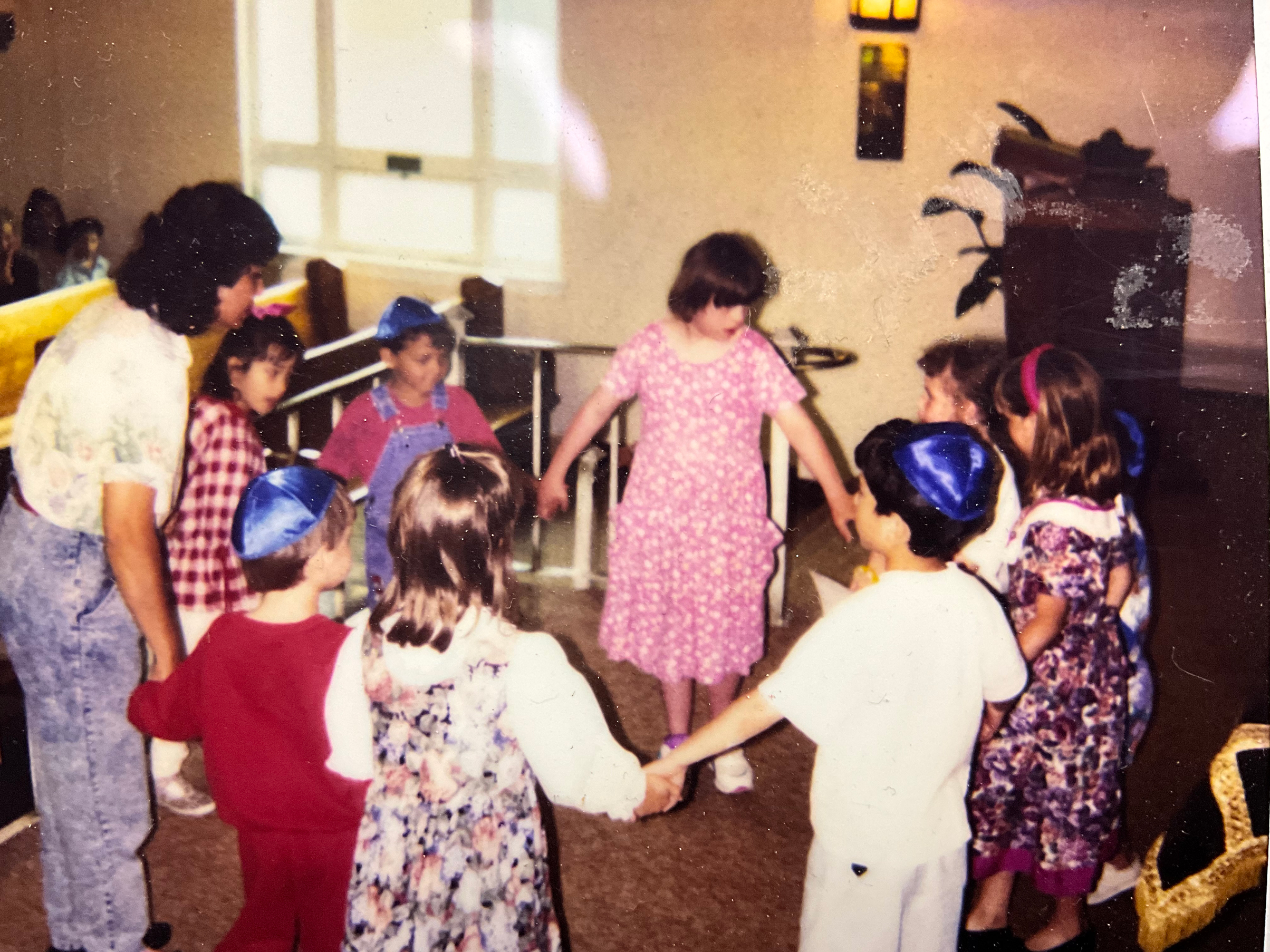 Image of young children and woman holding hands in a circle.